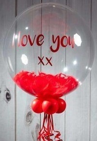 Love you printed on bubble transparent balloon with red rose petals inside and 3 red balloons outside at base