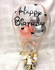 Print happy birthday Transparent balloon stuffed with 2 silver and 1 pink balloon tied to a basket with 4 ferrero rocher chocolates and 6 white roses