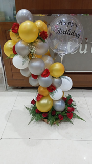 Balloon Garland made of mix colour balloons and red flowers basket circling a transparent balloon with print happpy birthday