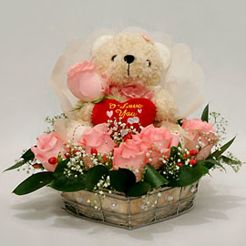 Small Teddy surrounded with Pink roses in a Basket