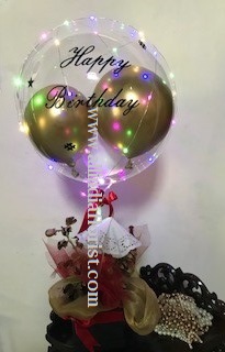 Print on balloon with happy birthday with led string fairy lights in a black box with dry flowers golden and red net and 5 red rose