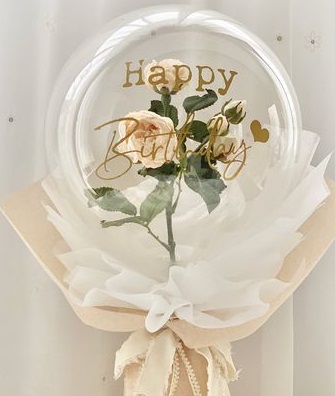 A bouquet of single clear balloon with happy birthday printed wrapped in white and jute with white rose inside