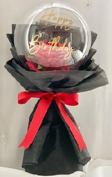 Print on balloon with happy birthday and red roses inside wrapping in black with red ribbon product is in bouquet shape